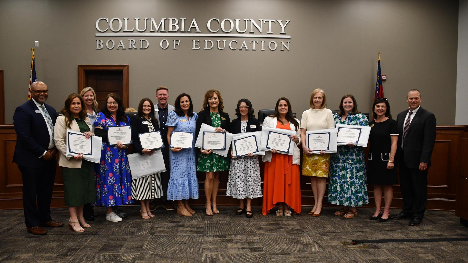 Group of people holding certificates in a formal setting.