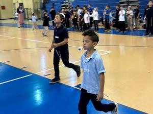 A boy balances a pom pom using a spoon.