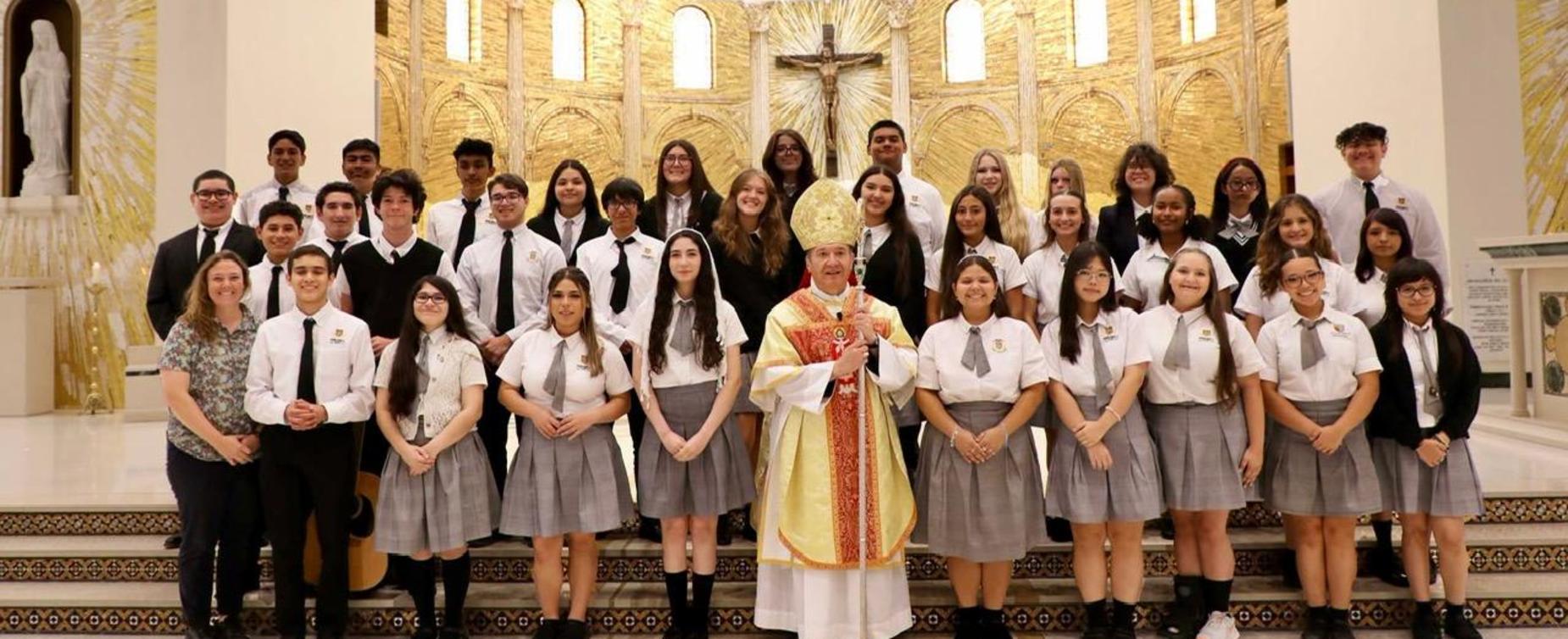 Group of students and a clergy member posing in a decorated church interior.