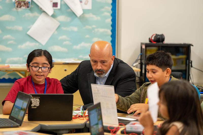 Superintendant Chait helps two students with chromebooks