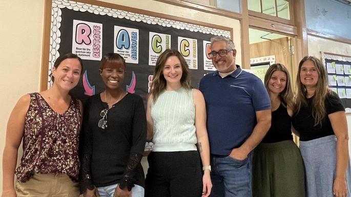 men and women in front of a bulletin board