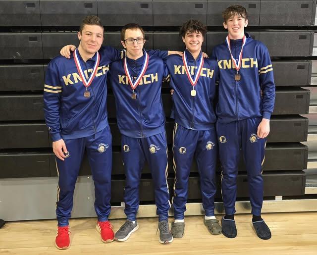four wrestlers in warm ups have medals around necks