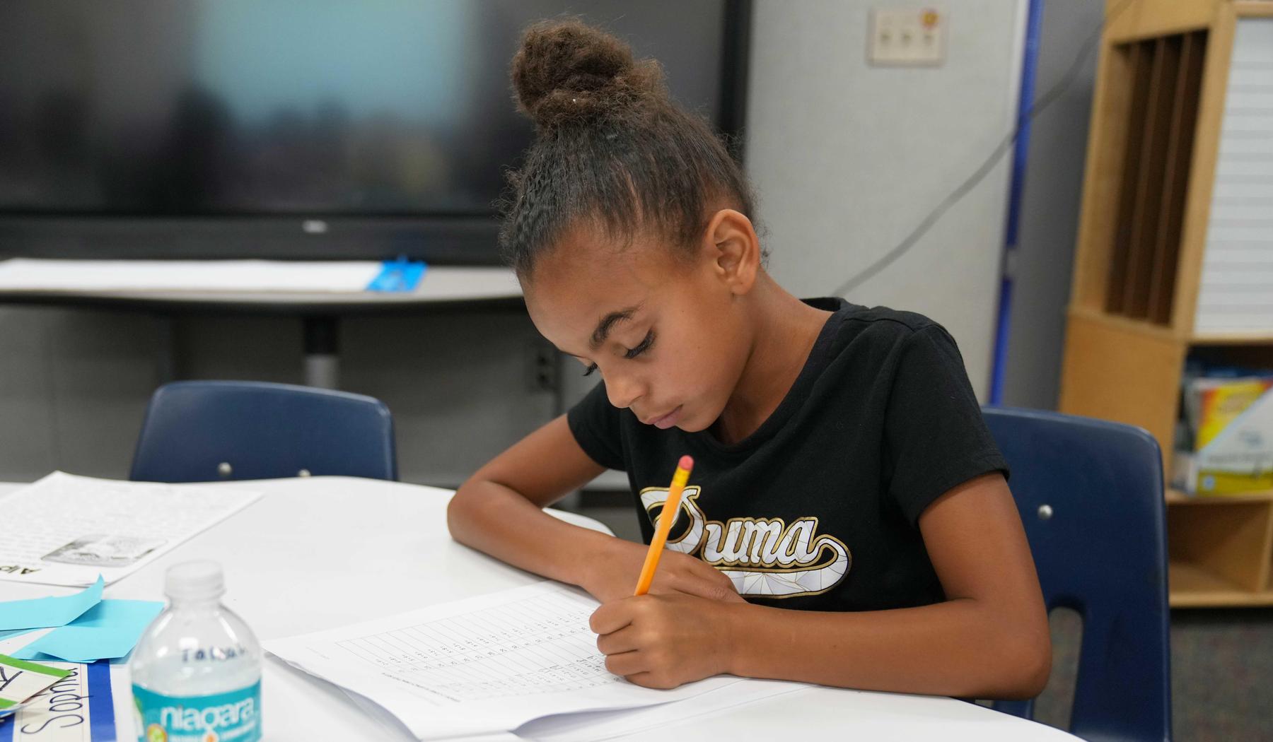 girl holding a pencil working on an assignment