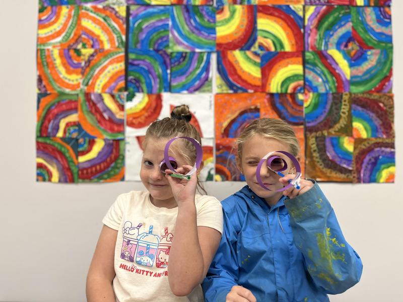 Students looking at camera through paper art
