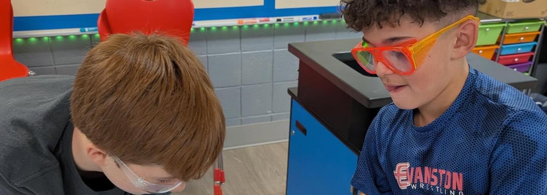 Two students engaged in a dissection, examining an animal specimen while wearing gloves and safety goggles.