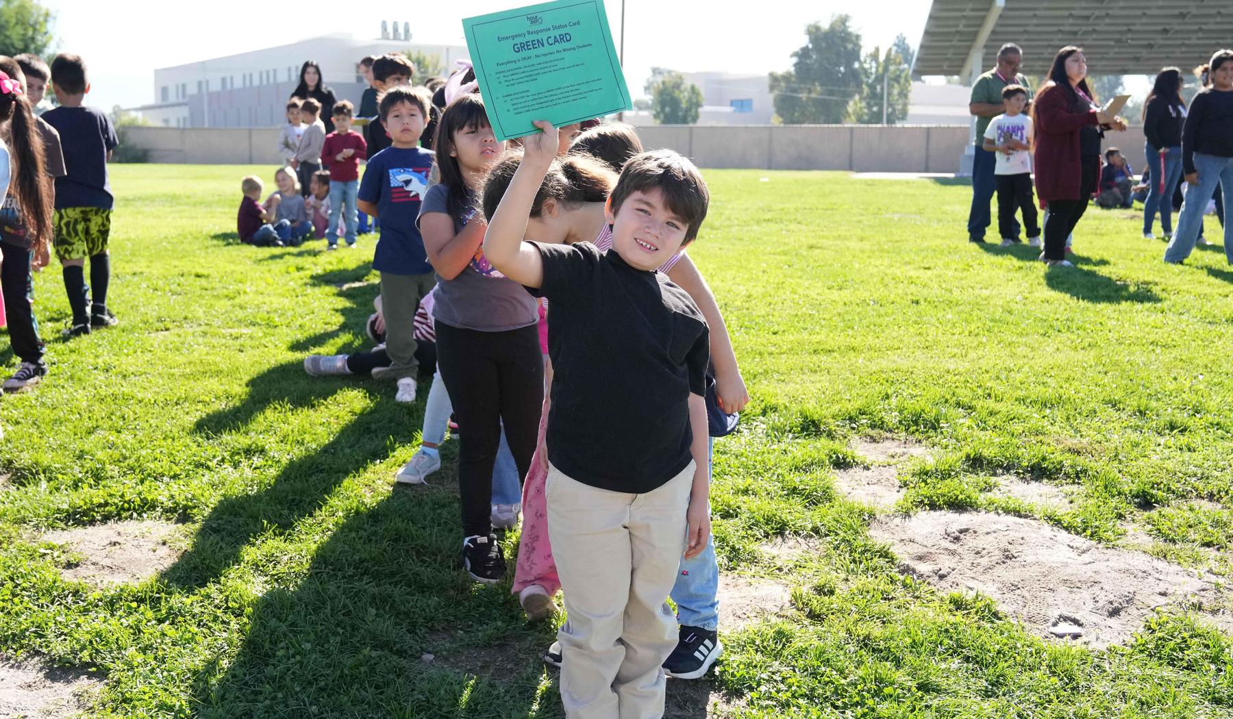 boy holding green card indicating all students accounted for after Great Shakeout Earthquake drill