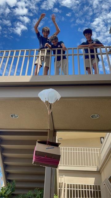 8th grade students watching egg drop design with parachute from the stairs