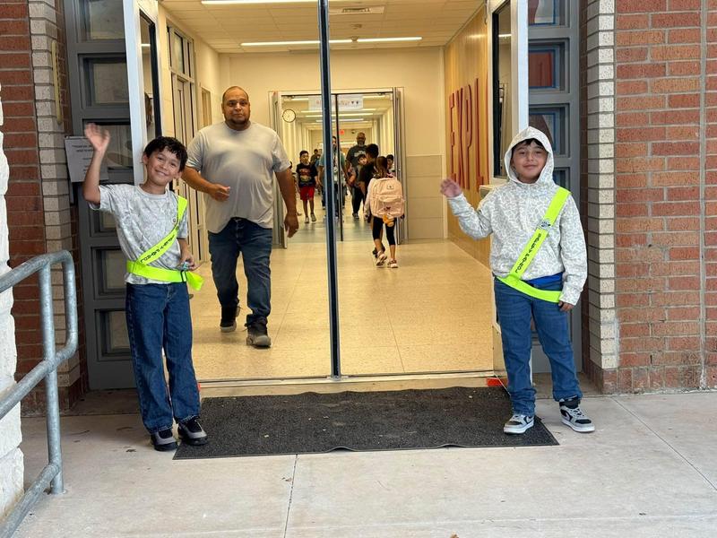 two boys waving wearing neon yellow patrol belt