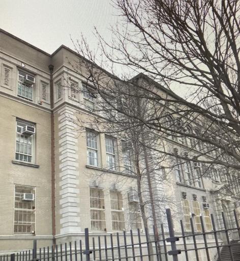 Historic brick building with large windows and bare trees in front.