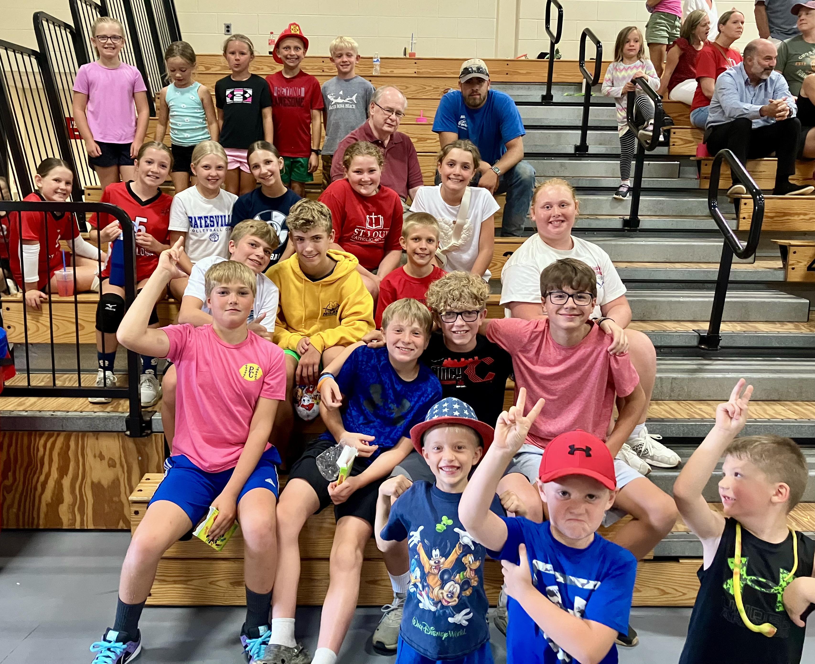 Students cheer with their peers and Father Stan at a volleyball game