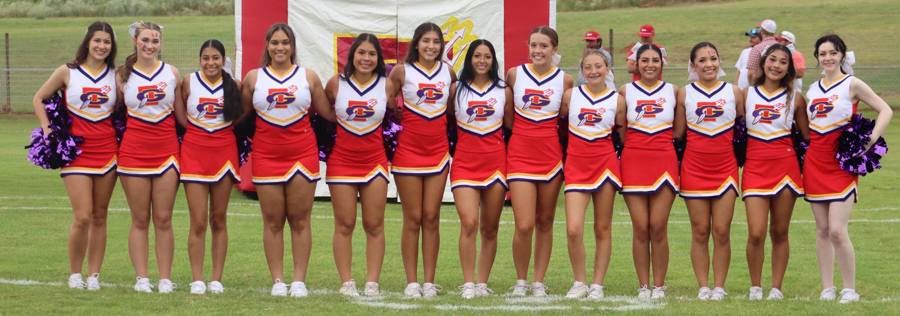 Cheerleaders in colorful uniforms posing together on the sidelines.