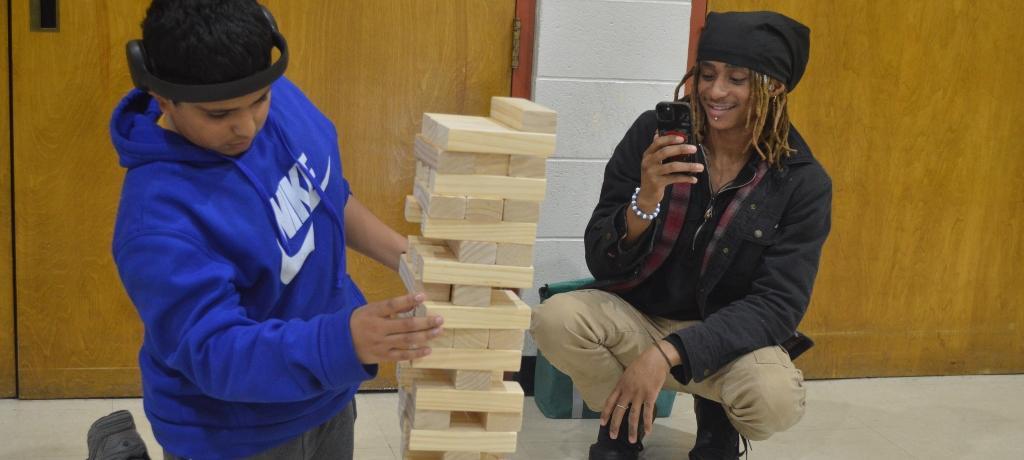 man videotapes boy as he makes a move in Jenga