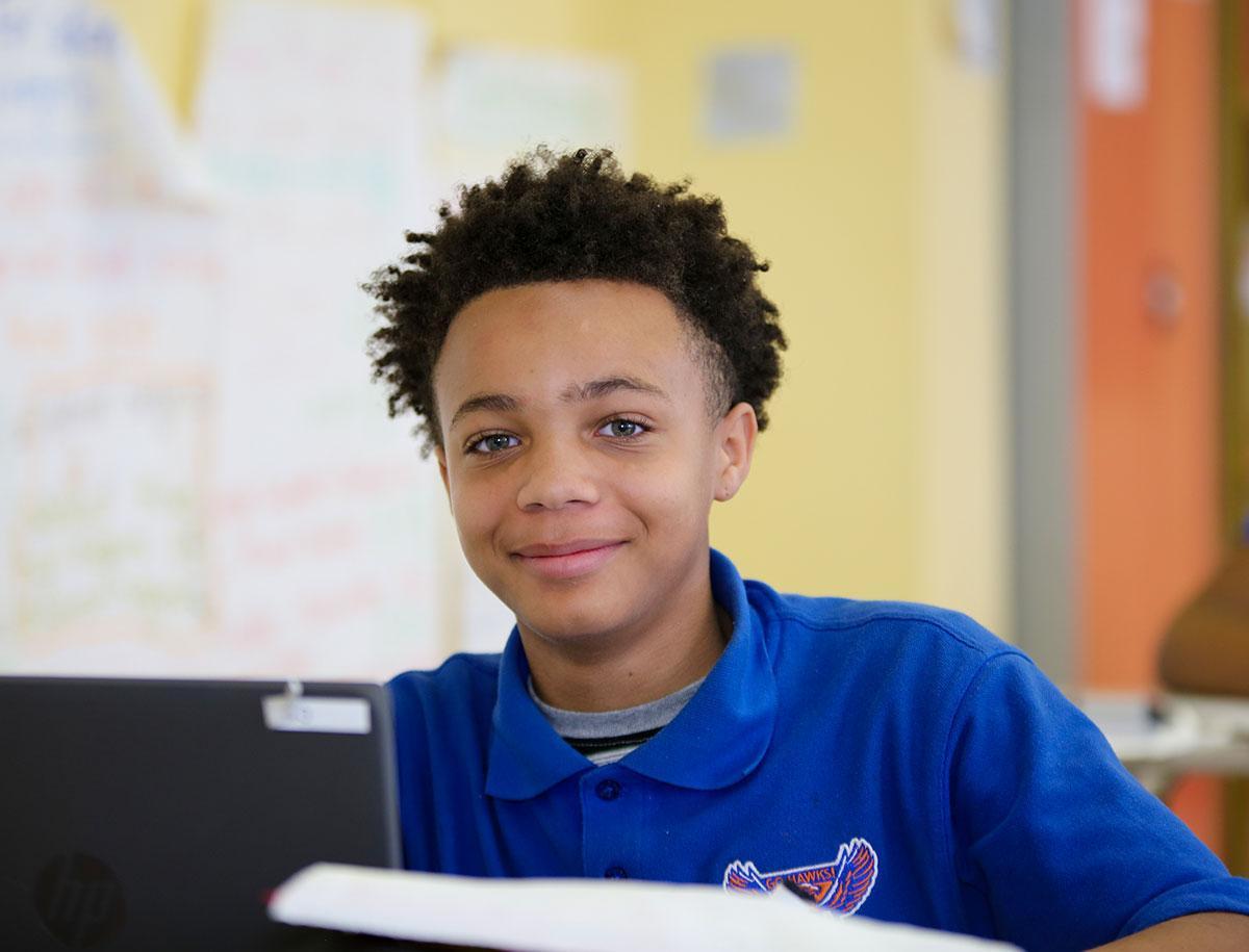 Elementary student smiling and posing in a classroom.