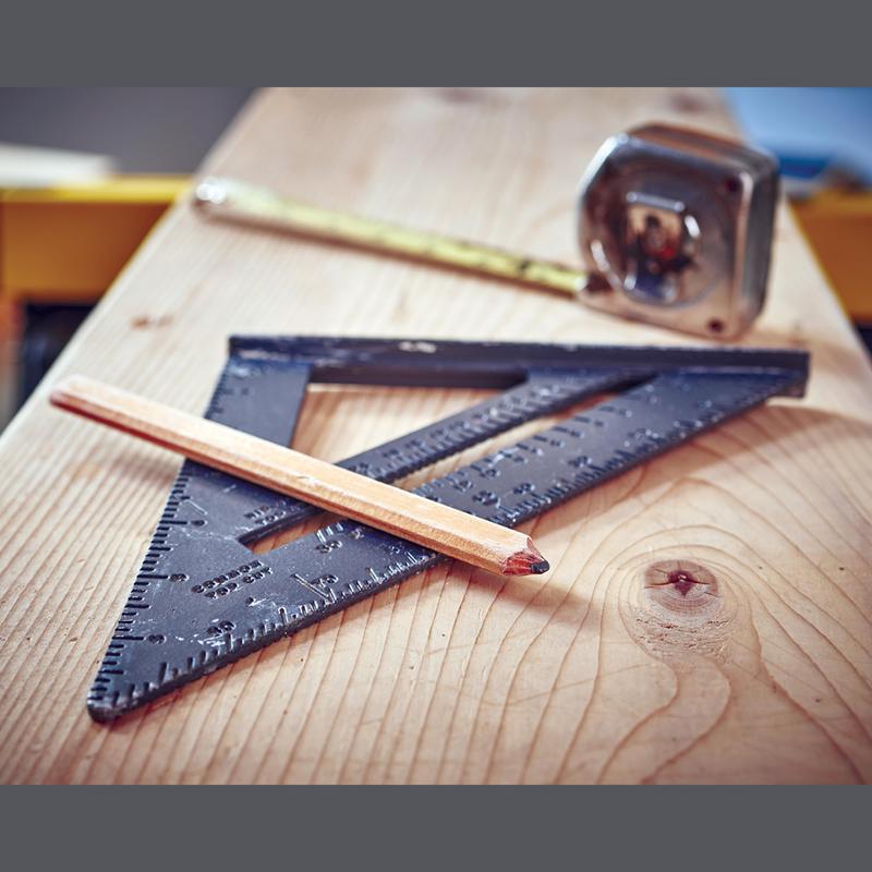 A carpenter's square and pencil on a wooden surface next to a tape measure.