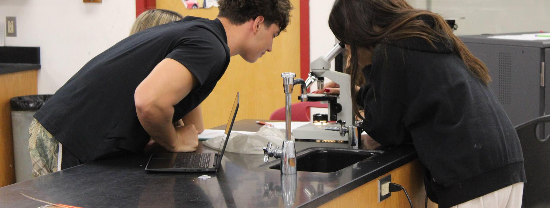 CHSW science students studying a specimen through a microscope.