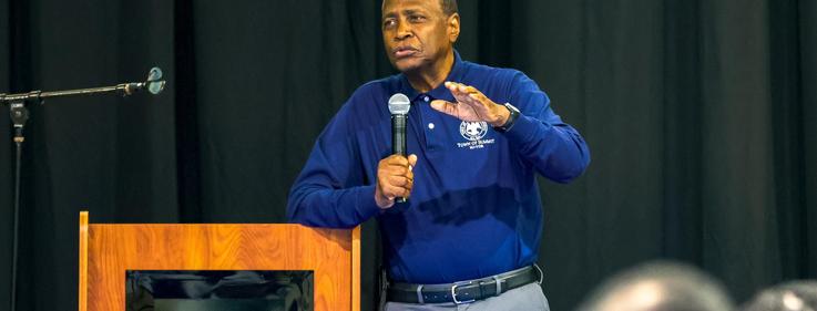 Man speaking at a podium with a microphone in a public setting.