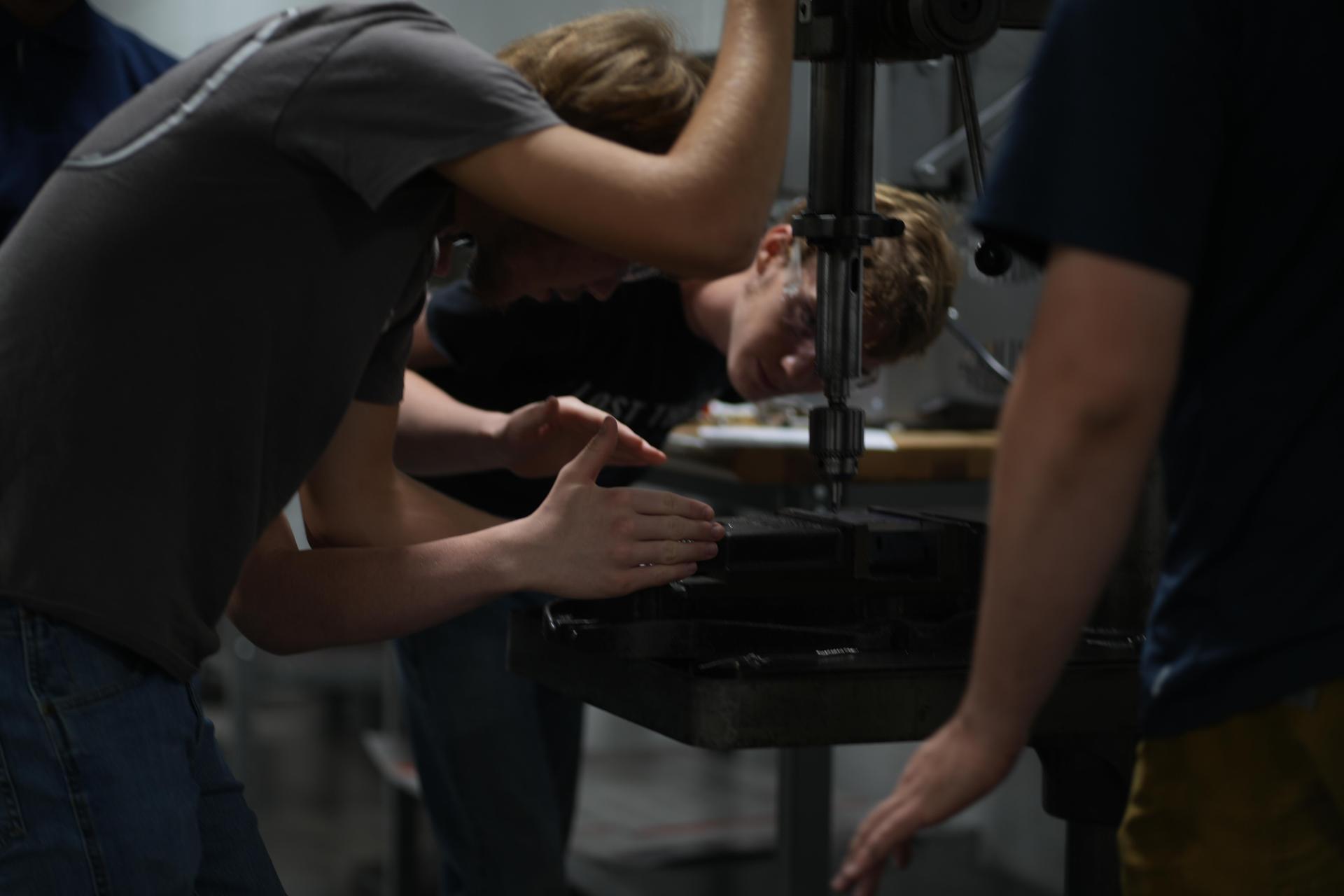 Students working on a project at a workshop, using tools and machinery.