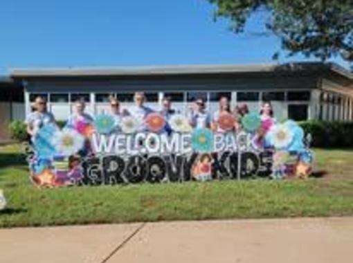 Our paraeducators, ready for a new school year. Sign reads: Welcome back, groovy kids. August 2025.