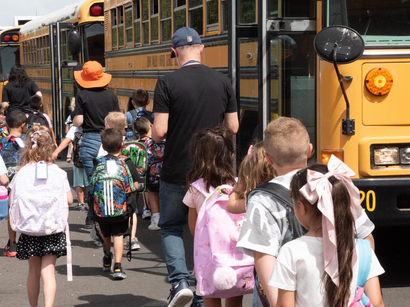 students walking with their teachers to the school bus