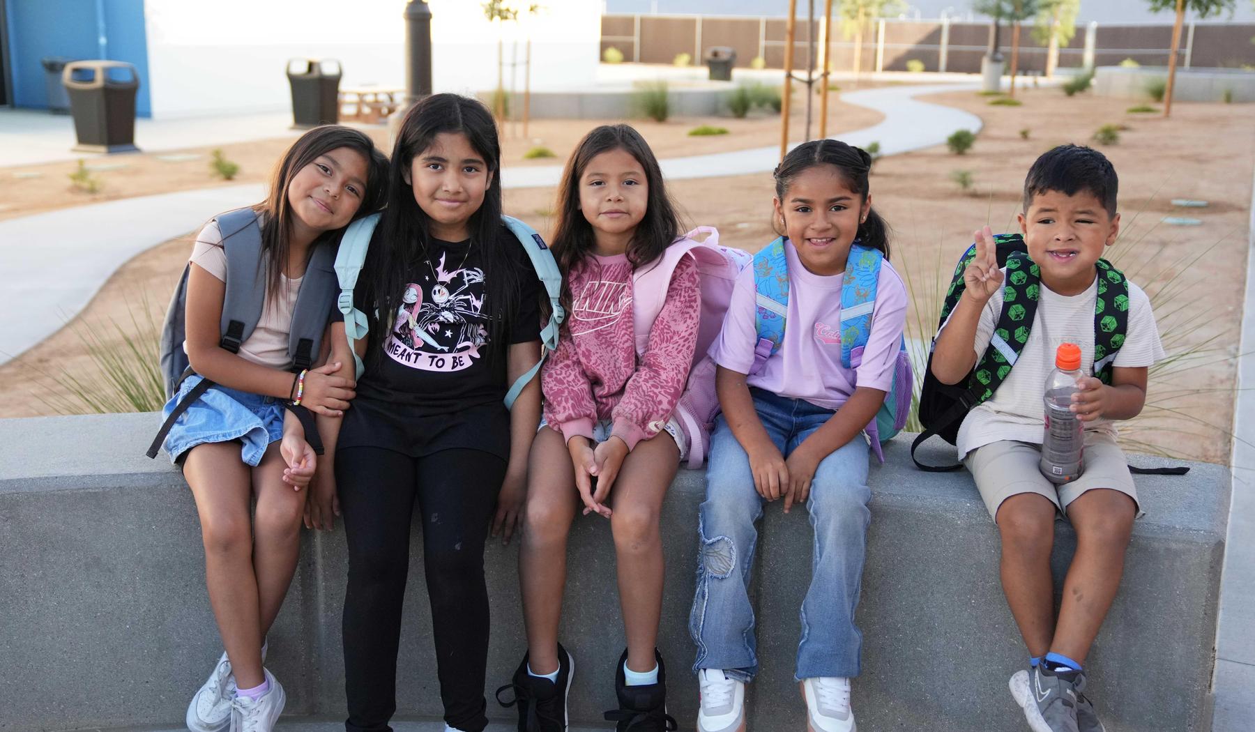 group of students sitting on cement bench waiting for school to start