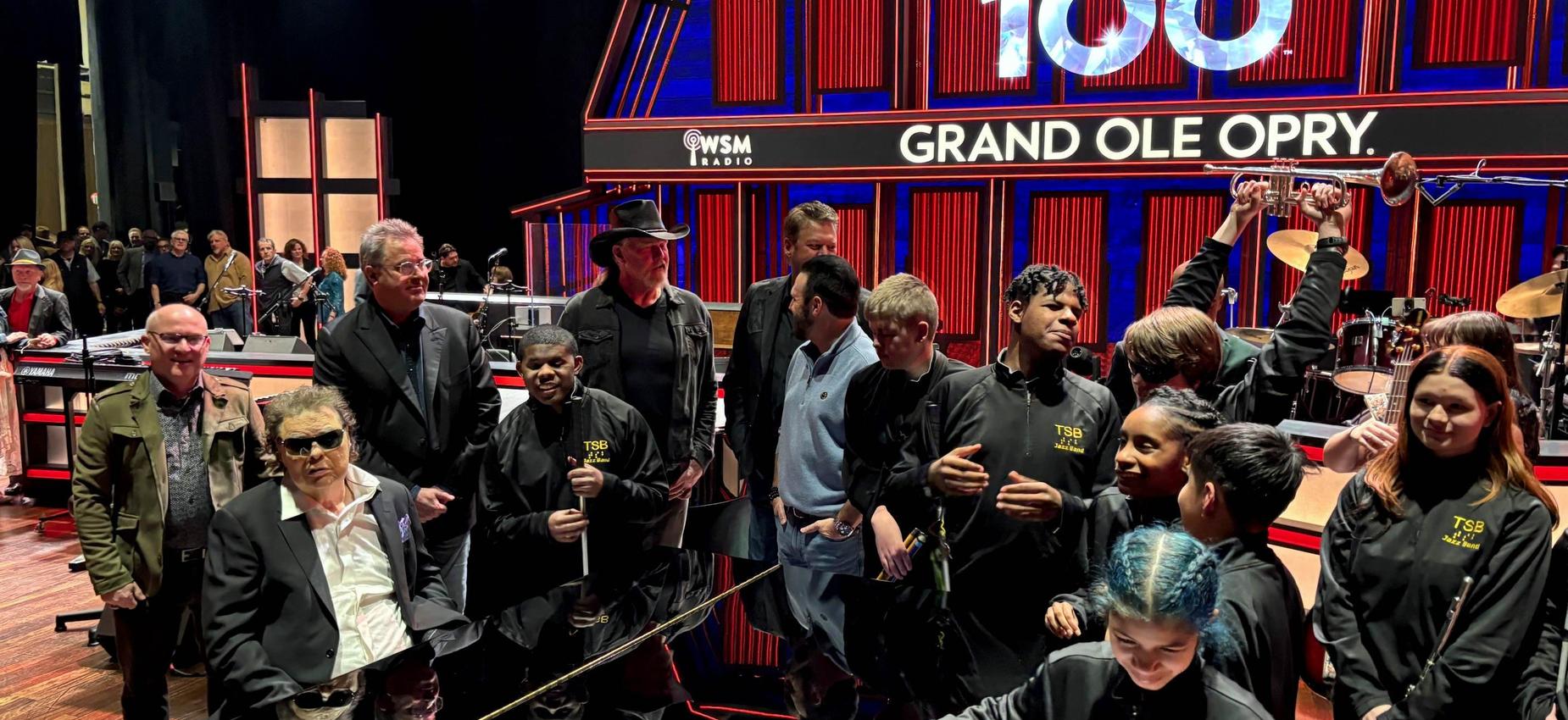 Group of people at the Grand Ole Opry studio with a performance backdrop.