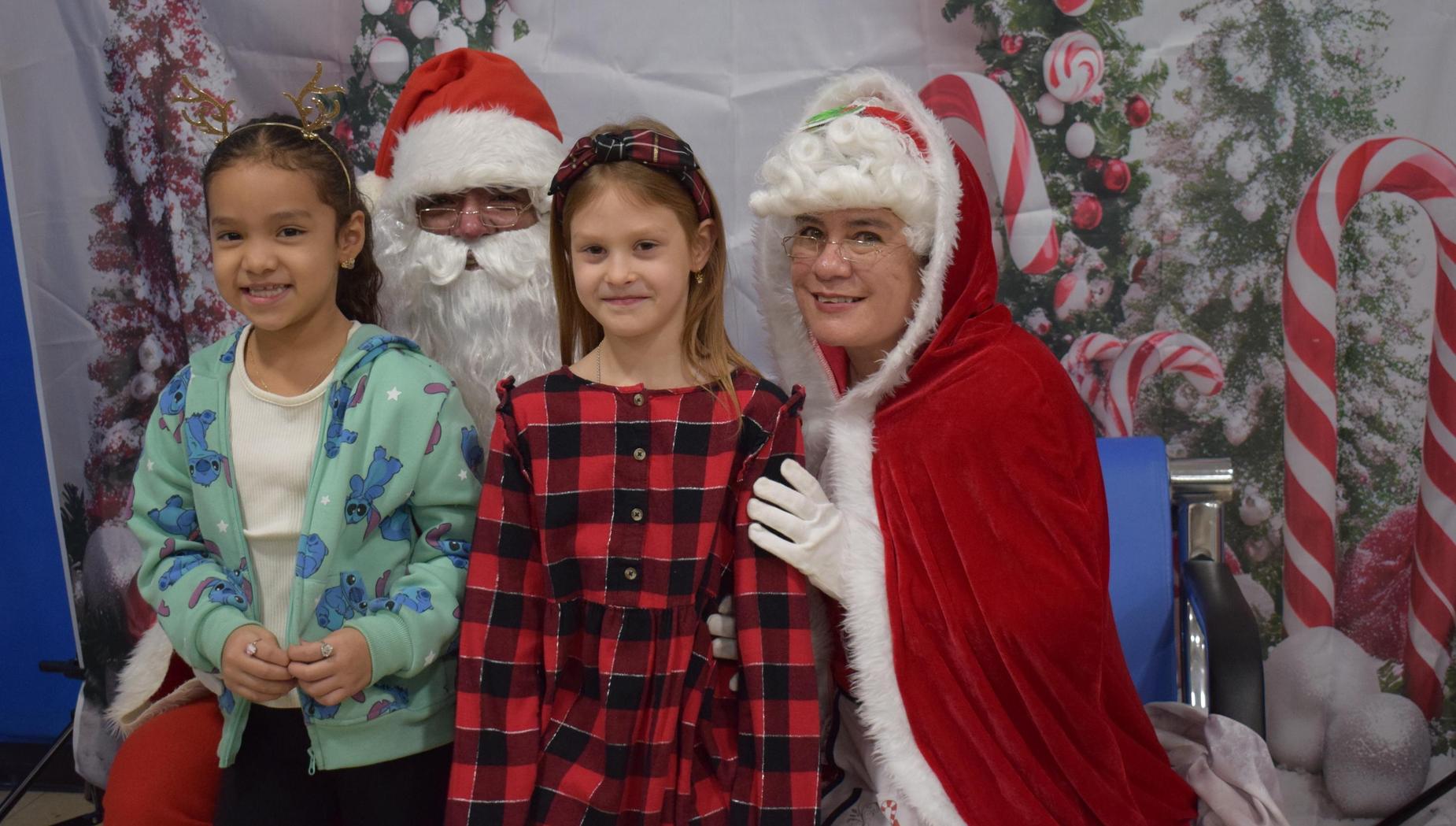 Children posing with Santa Claus and Mrs. Claus in festive attire.