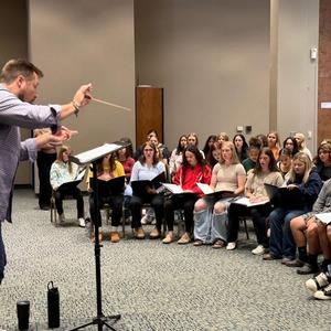 A group of students learning and practicing the music with conductor.