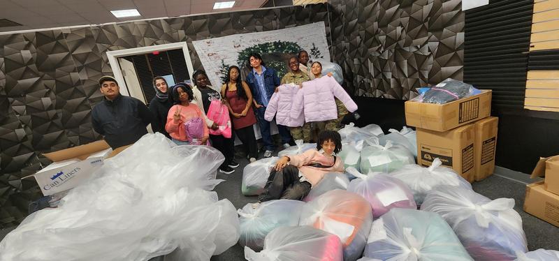 Students surrounded by plastic bags full of coats