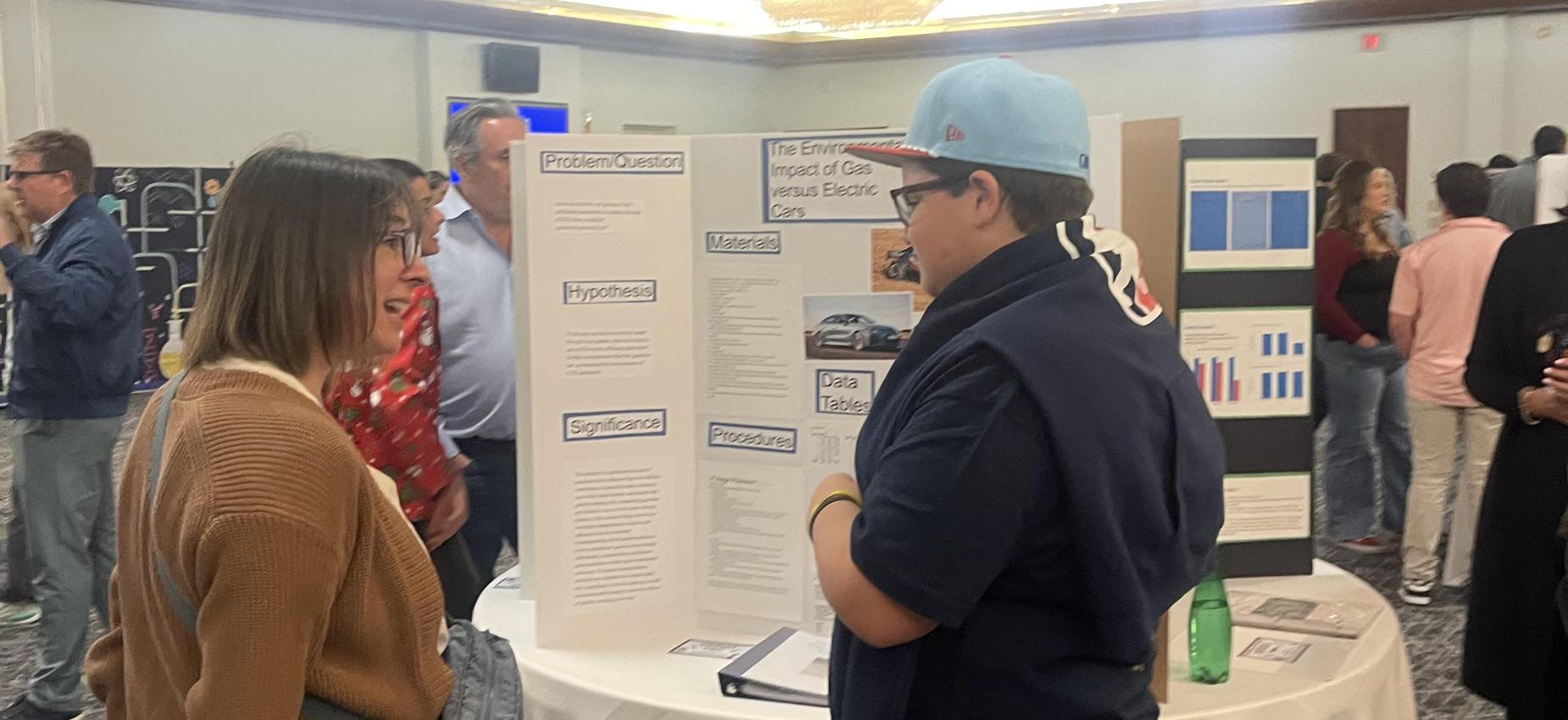 student presenting science fair project to a parent at Science Night