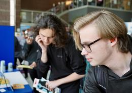 Two students examining materials at an event booth.