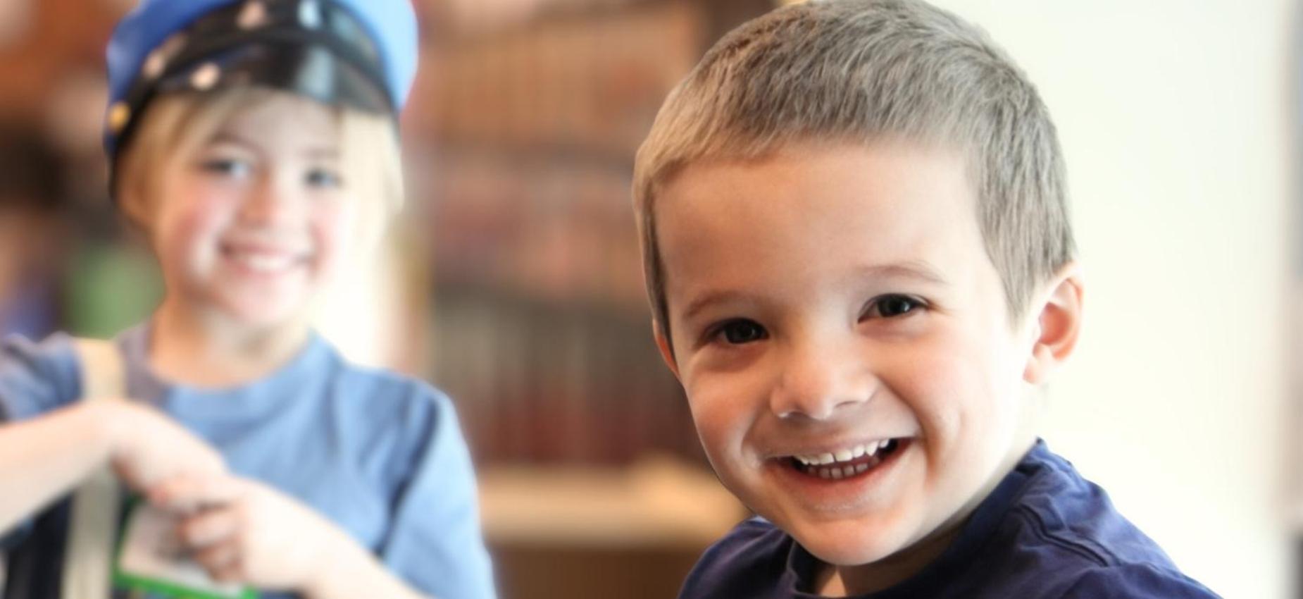 Smiling boy and girl in costumes posing happily indoors.
