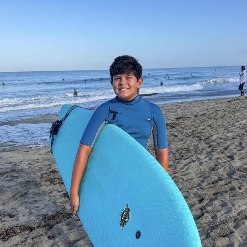 Boy in the sand with a surfboard