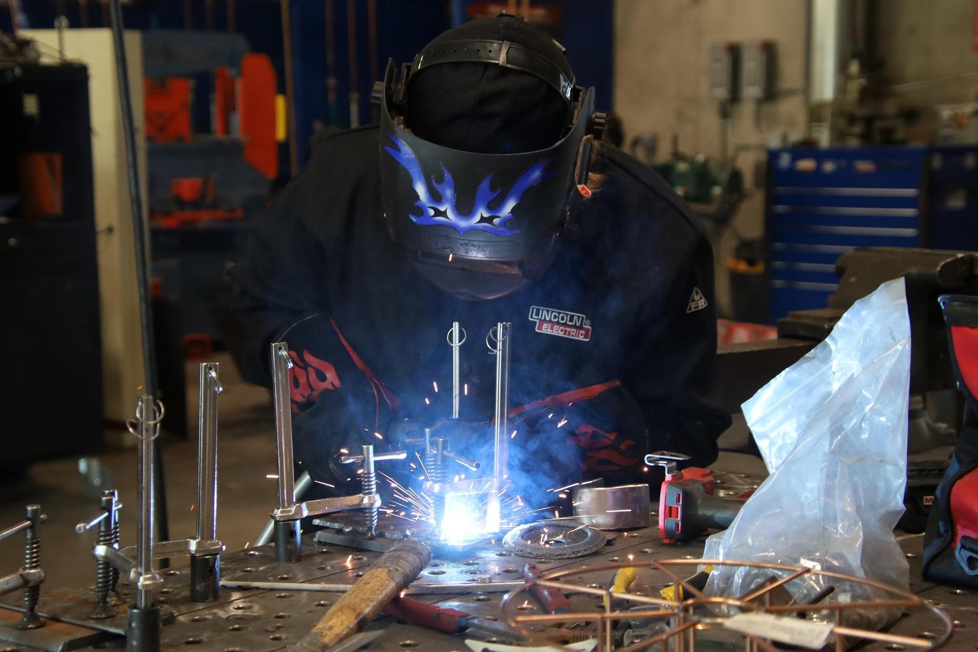 high school student welding in shop classroom
