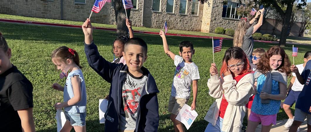 Children walking waving the American flag.