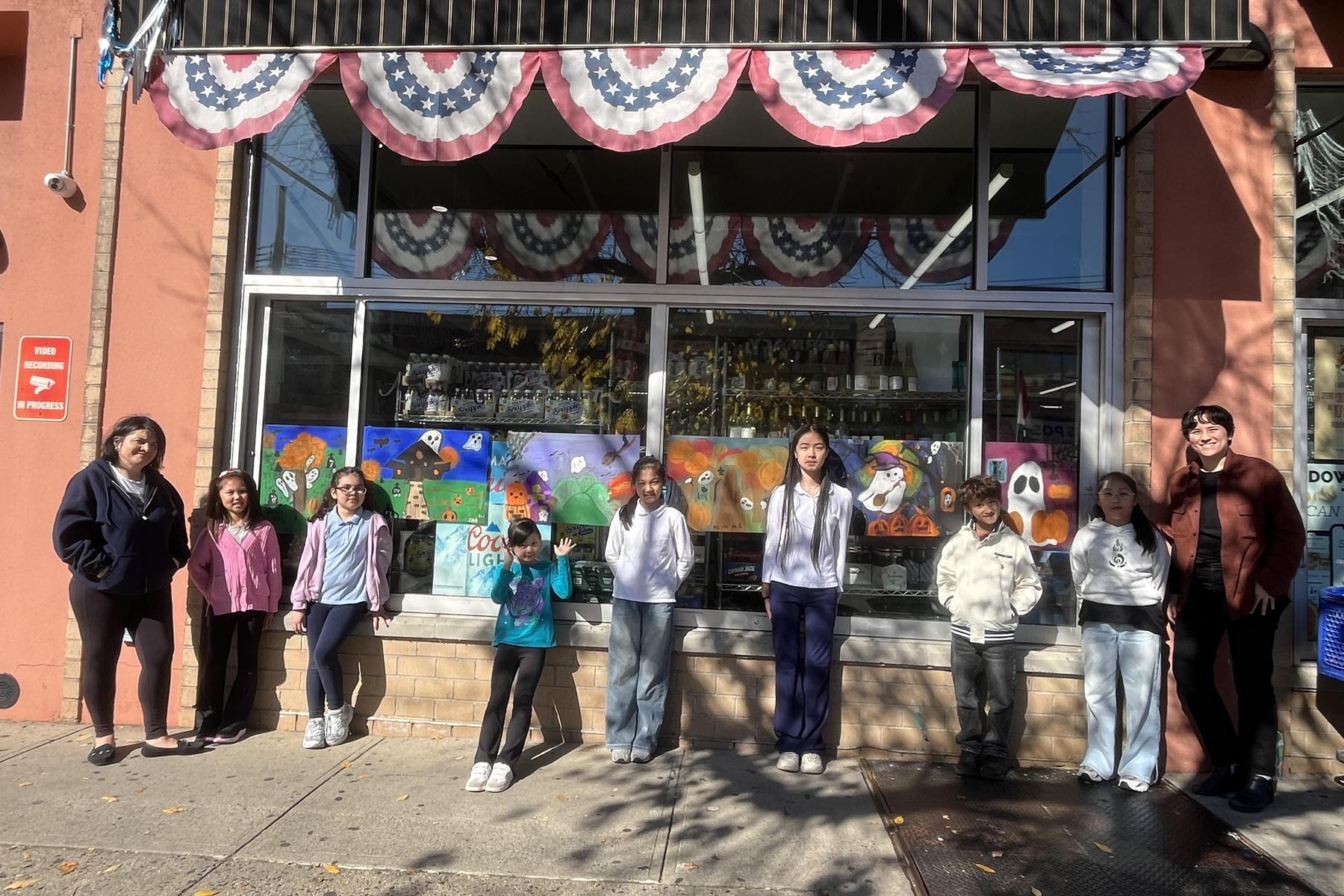Larger group of children and adults in front of a store with festive decorations.