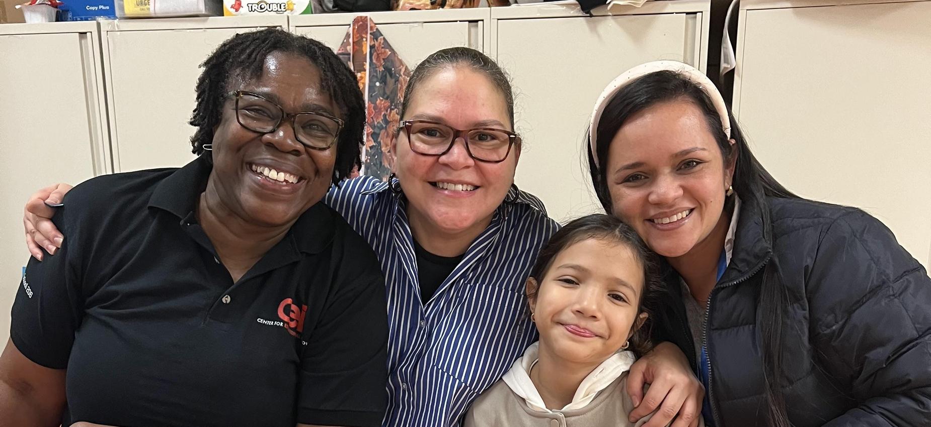 Two female staff members posing with a student and parent