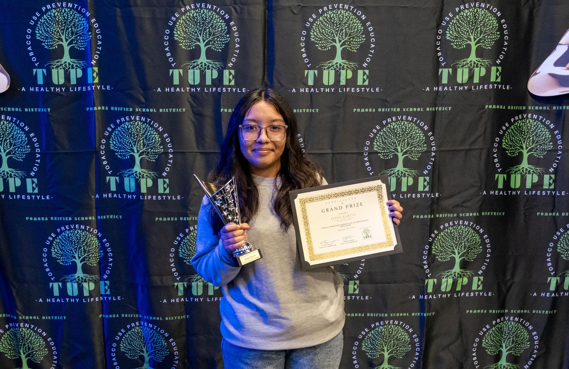Grand Prize winner holding trophy and certificate