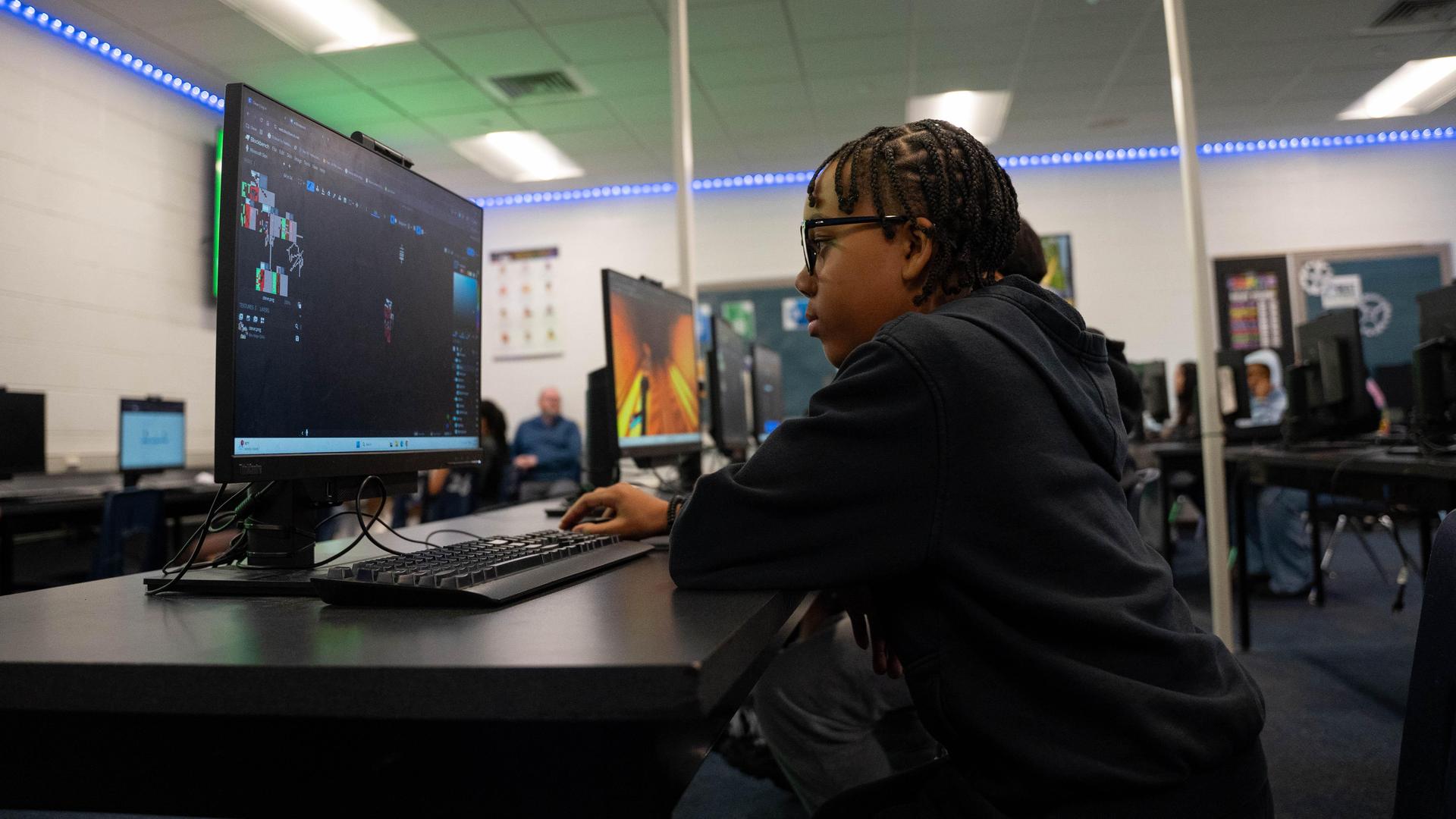 A student engages with a computer in a classroom setting.