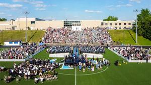 An aerial view of the class of 2026 commencement ceremony with high school in background