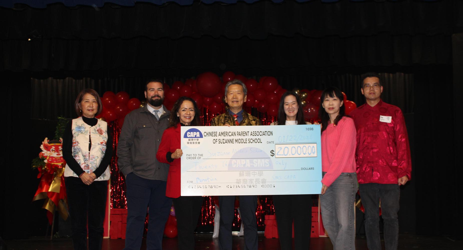 Group of people holding a large check for $200,000 at an event.