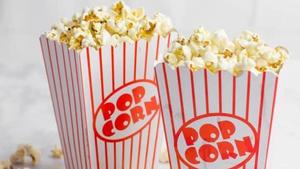 Two striped popcorn containers filled with buttery popcorn.