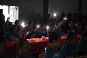 Students shine their flashlights on their phones during the United Way event.