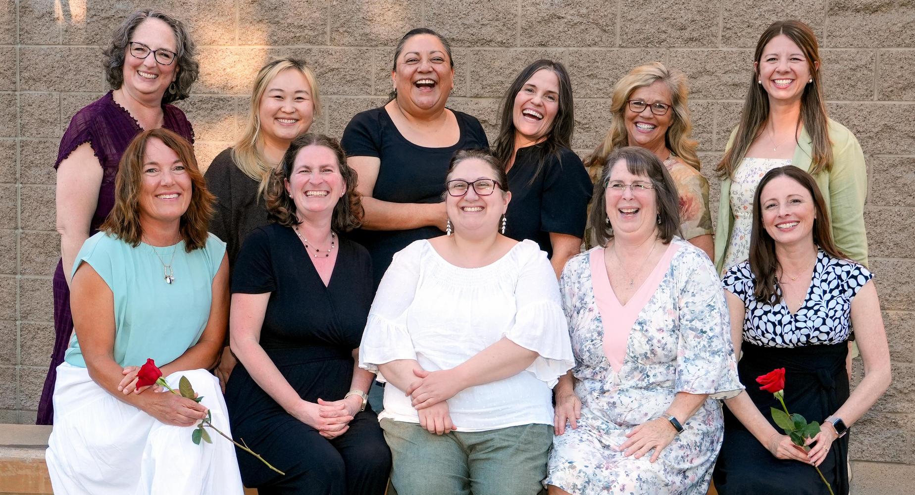 A group of teachers pose, smiling and laughing, at promotion