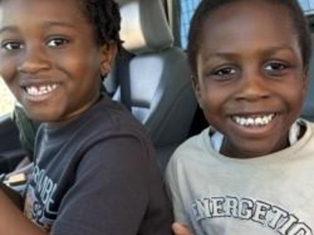 Two smiling boys sitting together in a car.