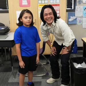 Student standing next to teacher in the classroom