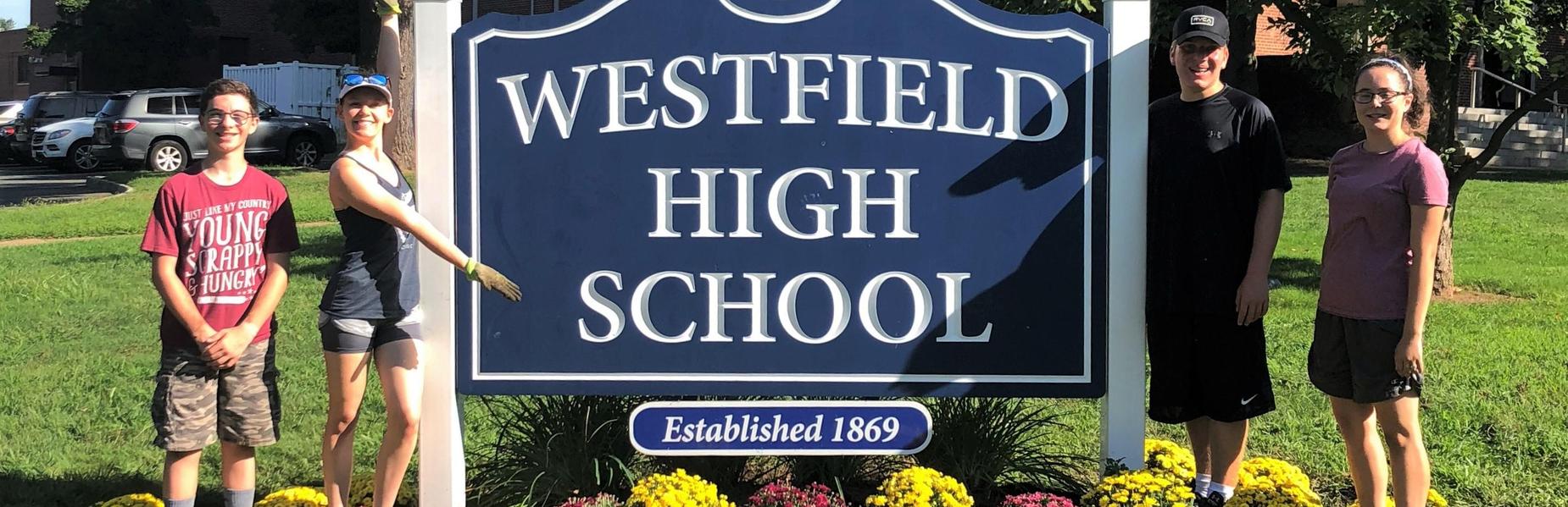 WHS band members help the PTO landscape committee beautify the WHS sign.