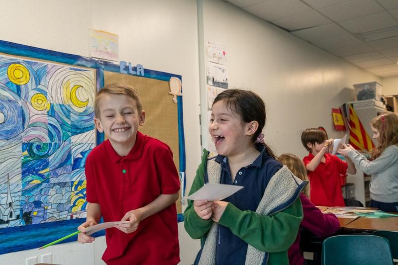 Two students at Arco Iris Spanish Immersion school share a laugh in a classroom.