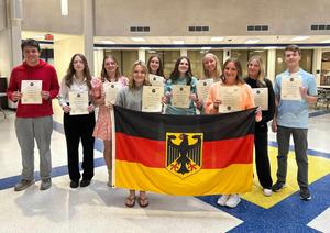 A group of students holding certificates and posing with the German flag