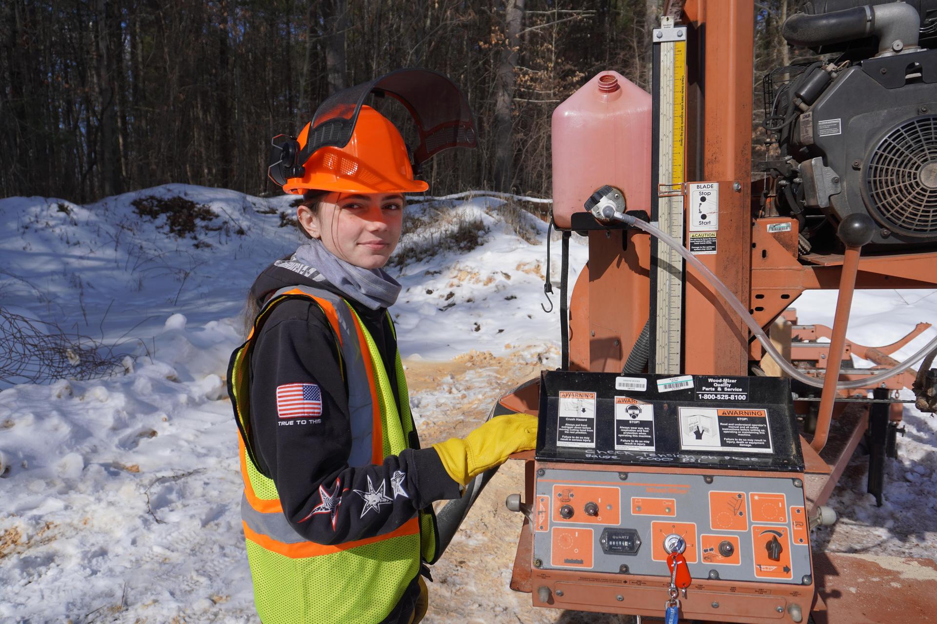 environmental conservation student in front of wood splitter