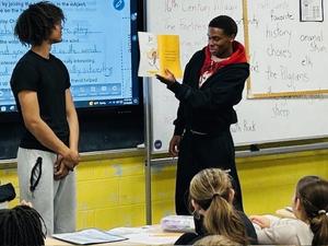 two high school boys read to children